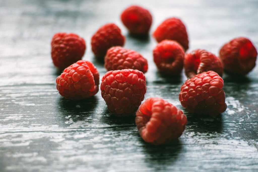 A detailed shot of vibrant raspberries scattered on a rustic wooden board, evoking freshness.