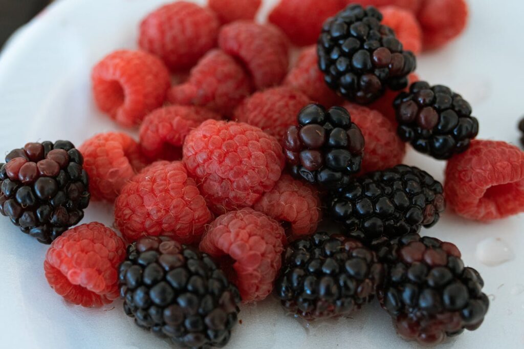 Vibrant close-up of fresh raspberries and blackberries on a plate.